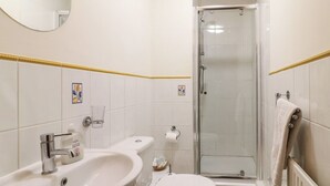 A bathroom with a sink, toilet, and glass shower enclosure. - Stables (Derby)