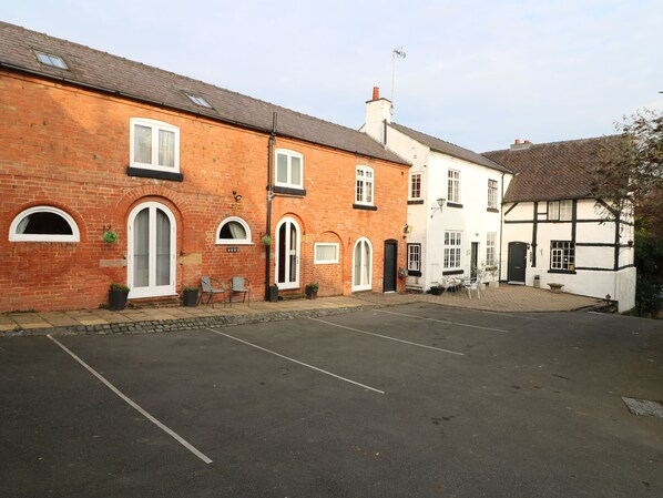A street with a row of traditional brick and timber-framed buildings, a paved road, and a clear sky.