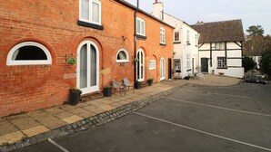 A row of traditional brick and timber-framed buildings with arched windows and a paved street. - Stables (Derby)