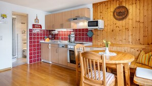 Una cocina con armarios de madera, un microondas y un comedor con mesa y sillas de madera.