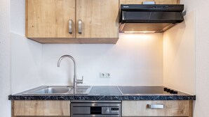 Een moderne keuken met houten kastjes, een roestvrijstalen spoelbak, een ingebouwde vaatwasser en een zwarte afzuigkap.