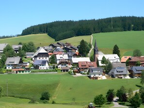 Un village avec des maisons, une église et une colline en arrière-plan.