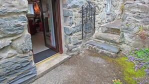 A stone building with a wooden door and a metal gate. - Y Beudy (Llanbedr)