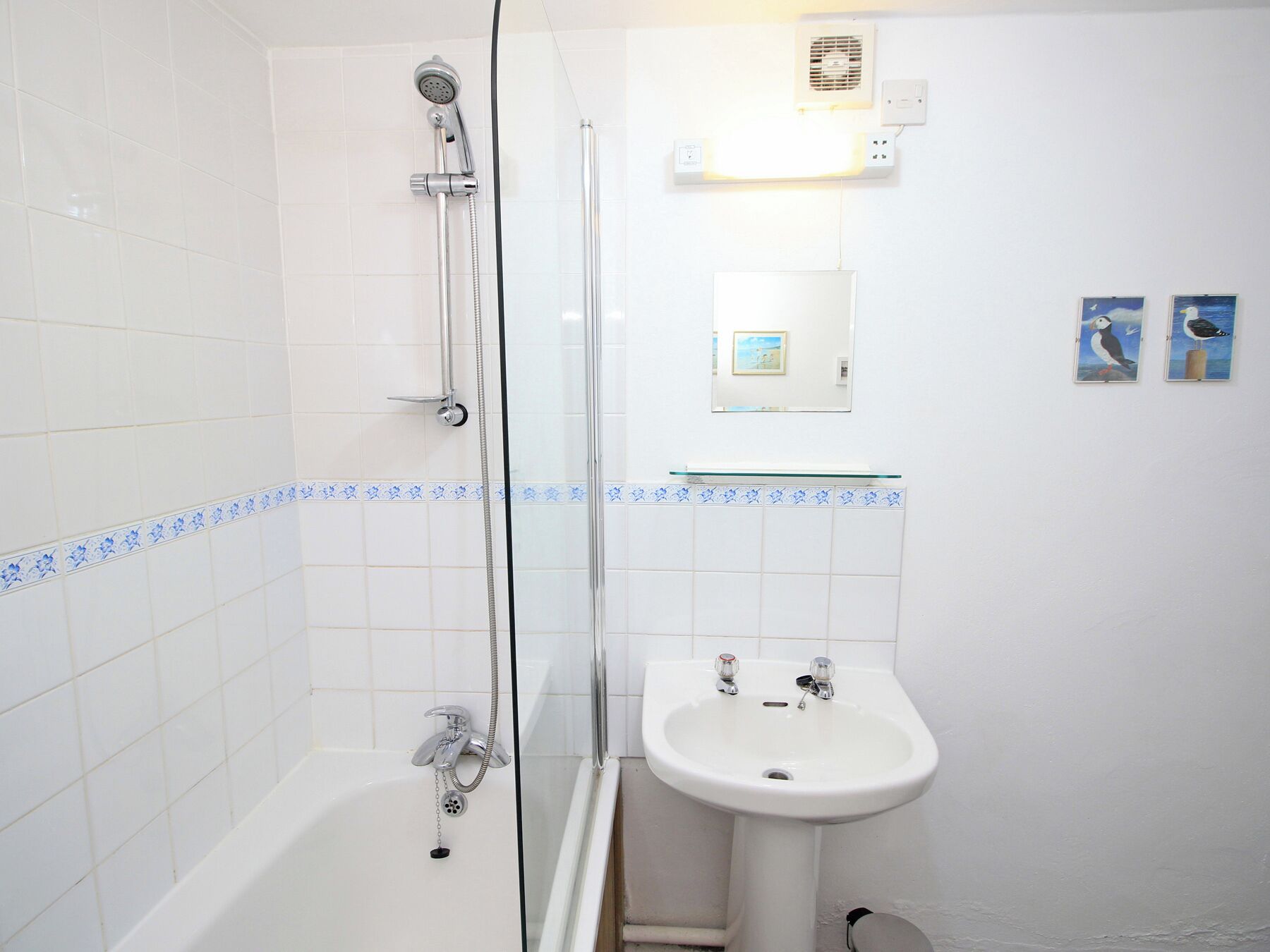 A bathroom with a shower, a sink, and a mirror.