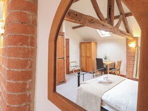 Un dormitorio con una cama, un armario de madera, un escritorio con silla y una ventana.