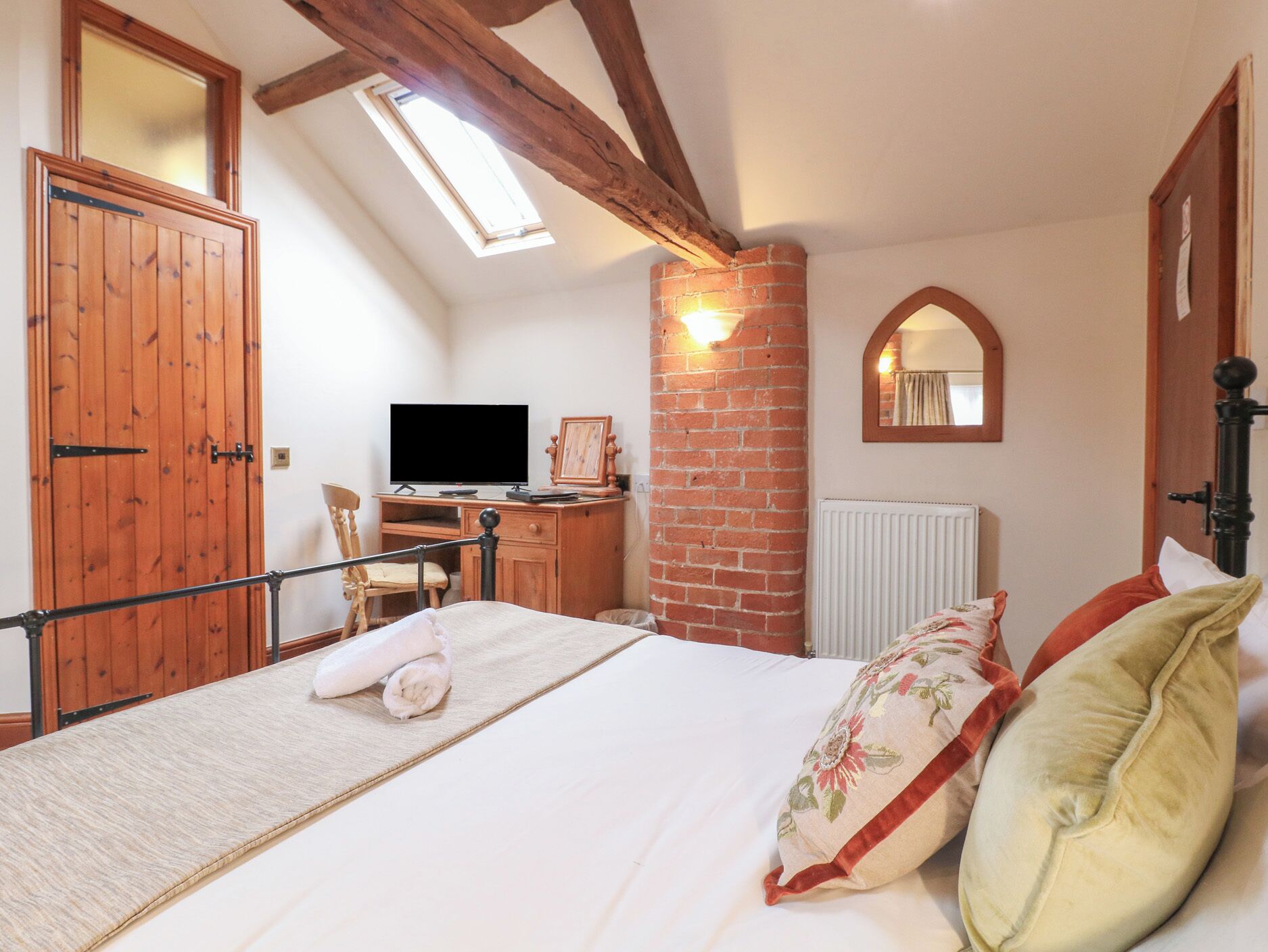 Ein Schlafzimmer mit Bett, Schreibtisch, Fernseher, Fenster und Spiegel.