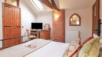 Ein Schlafzimmer mit Bett, Schreibtisch, Fernseher, Fenster und Spiegel.