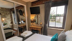A hotel room with a bed, a wooden desk, a mirror, and a TV. - Cedar Cottage (Barnard Castle)