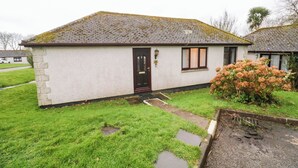 A small, single-story house with a white exterior and a dark brown door.