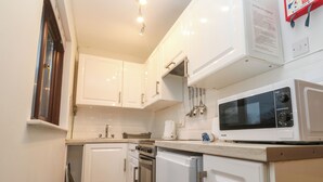 A compact kitchen with white cabinets, a microwave, a stove, and a sink.
