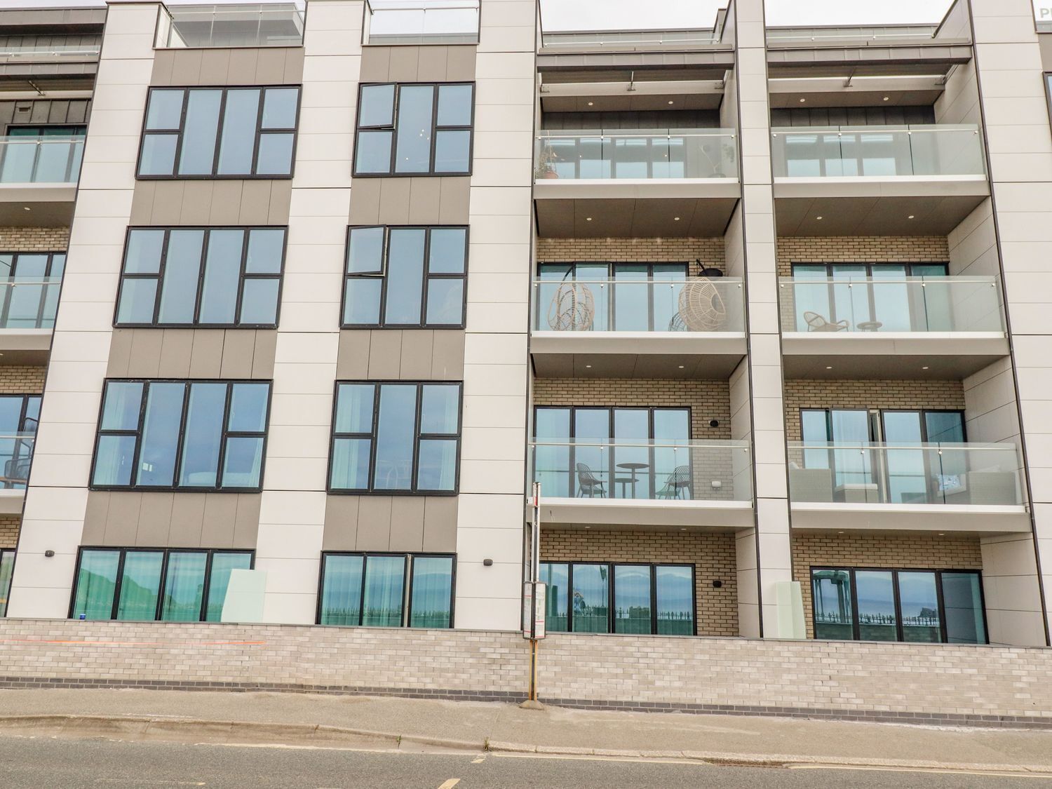 Un immeuble à plusieurs étages doté d’une architecture moderne, caractérisé par de grandes fenêtres et des balcons.