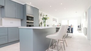 A modern kitchen with grey cabinets, a central island, and bar stools. - Apple Tree Cottage (Preston)
