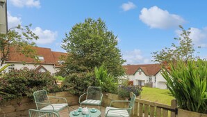 A patio with four chairs and a table, surrounded by a wooden fence and various plants. - Sea Rose (Cardigan)