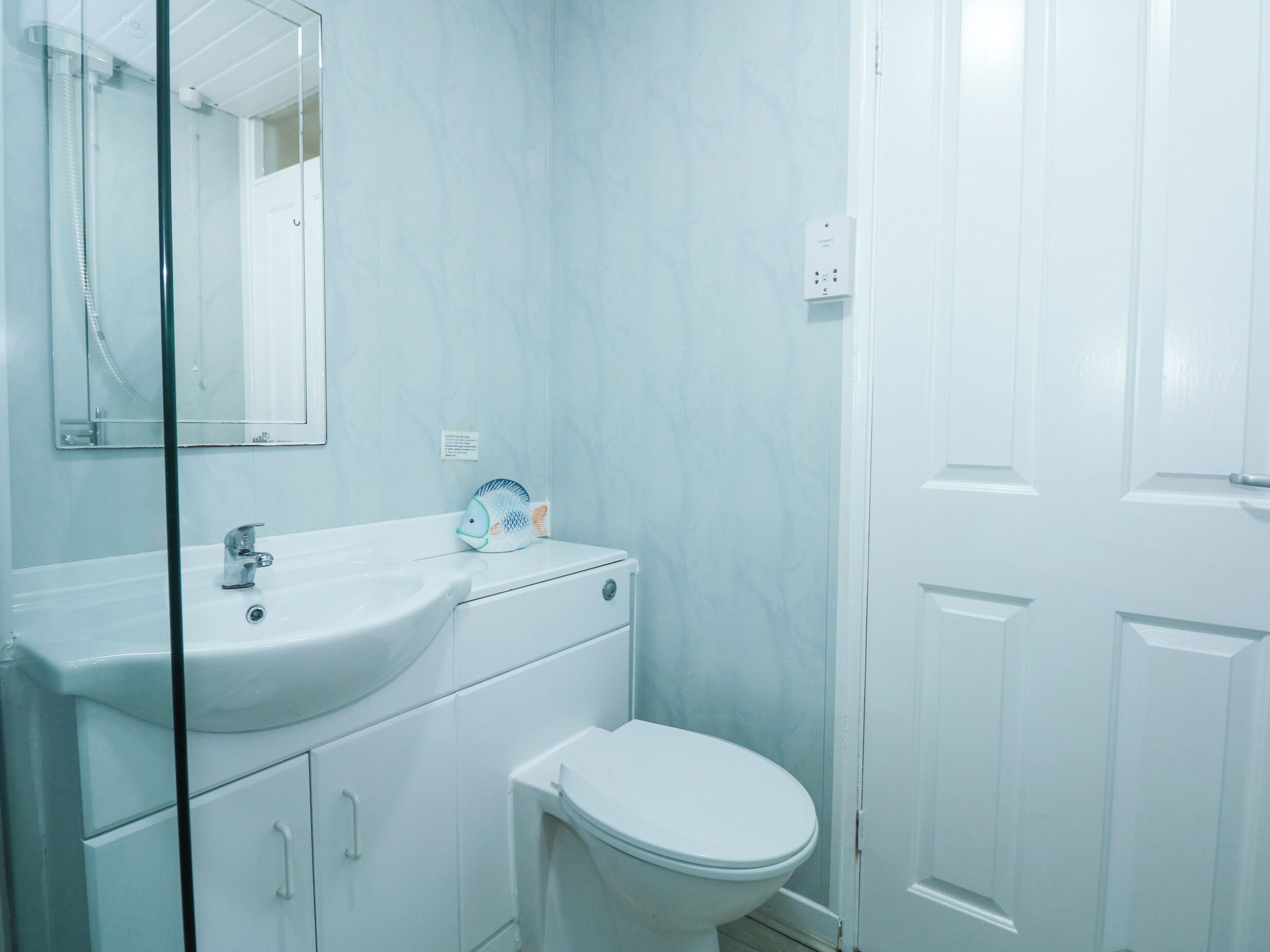 A bathroom with a white sink, mirror, and toilet.