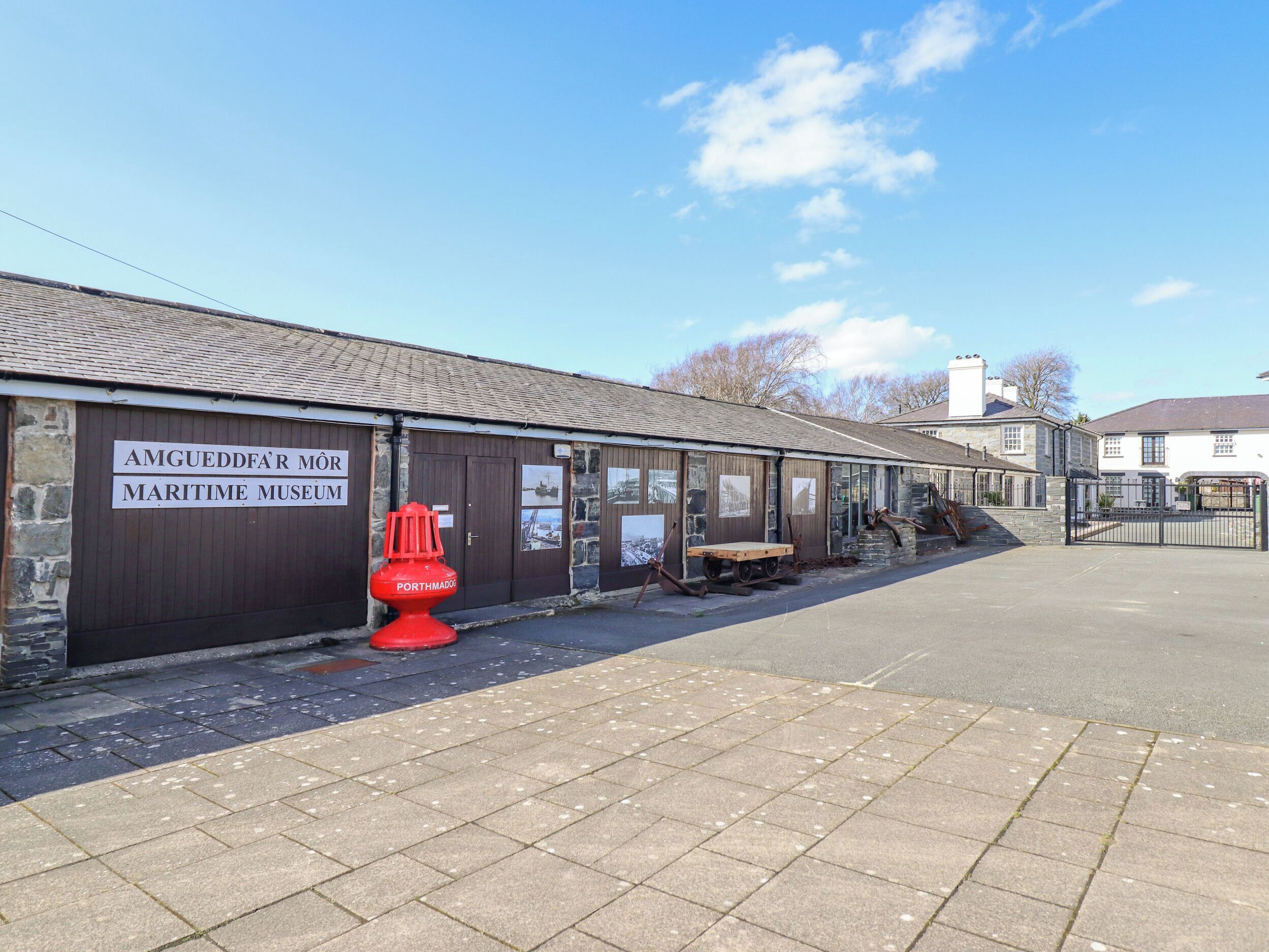 Un museu marítim amb un cartell que diu "AMGUEDDFAR MÔR MARITIME MUSEUM" i un hidrant vermell identificat com a "PORTMADOC".