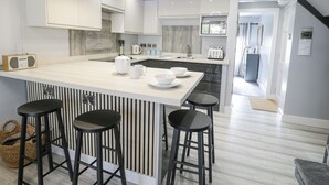 Et moderne køkken med en central ø, barstole, en radio og udsigt til opholdsstuen.