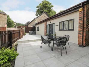 Un espace patio aménagé avec une table et des chaises, un mur en briques et une clôture en bois.
