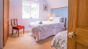 Une chambre avec un lit simple, une chaise, une fenêtre et une porte.