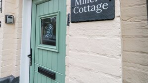 A door with a sign reading "Miller's Cottage" and a mailbox on the wall. - Miller's Cottage (Dorchester)