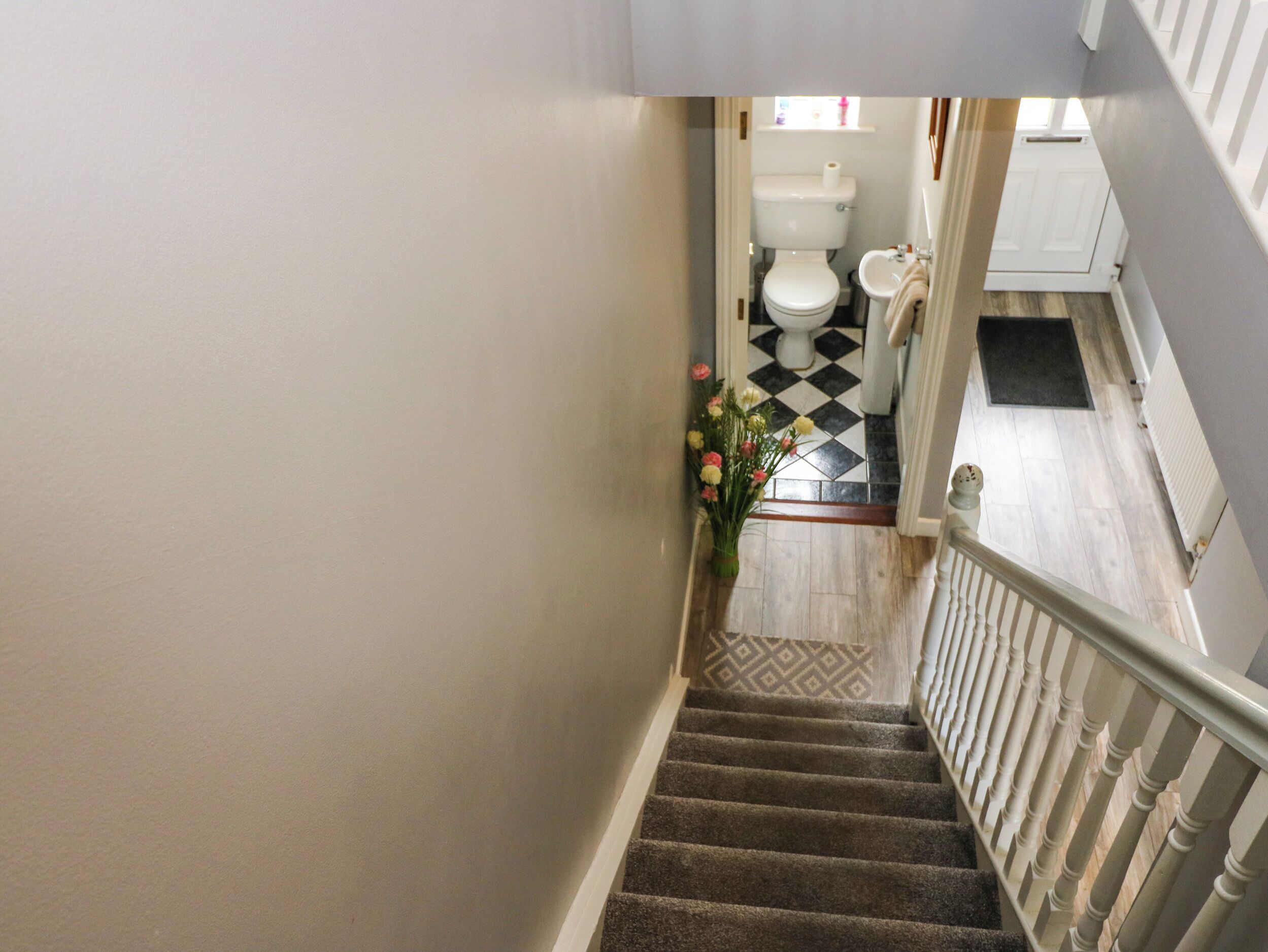 Un escalier menant à une salle de bain équipée de toilettes, d’un lavabo et d’un carrelage décoratif.