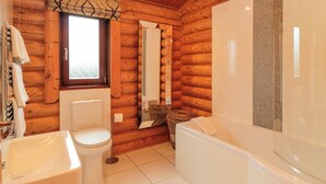 Un baño de cabaña de madera con inodoro, lavamanos y bañera.