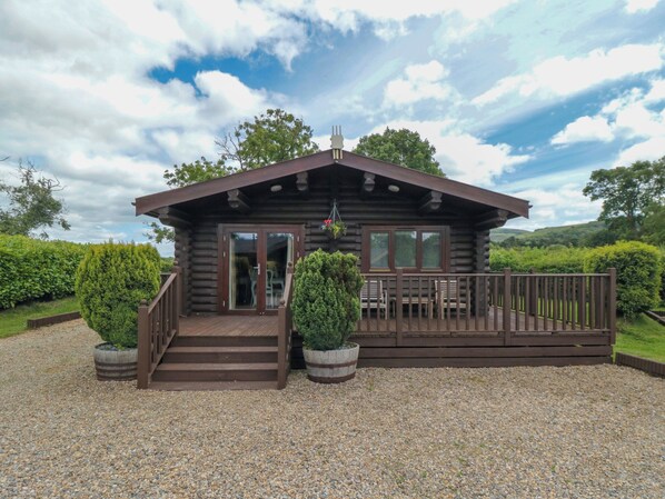 A log cabin with a wooden deck, a covered porch, and a gravel driveway. - Endeavour Lodge 4 (Middlesbrough)