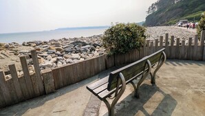 A wooden bench by a rocky beach with a wooden fence and a view of the sea. - Folly Cottage (Narberth)