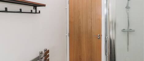 A bathroom with a shower, a wooden door, and a towel rack.