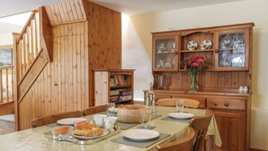 Ein Essbereich mit einer Holztreppe, einem Holzschrank mit Glastüren und einem Tisch, der mit Tellern und Gläsern gedeckt ist.