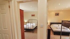 A hotel room with two beds, a door, and a carpeted floor. - Valley View (Cleator Moor)