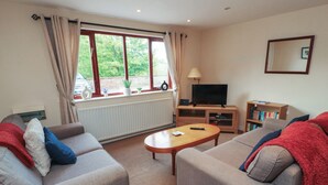 A living room with two sofas, a coffee table, a TV, and a bookshelf. - Valley View (Cleator Moor)