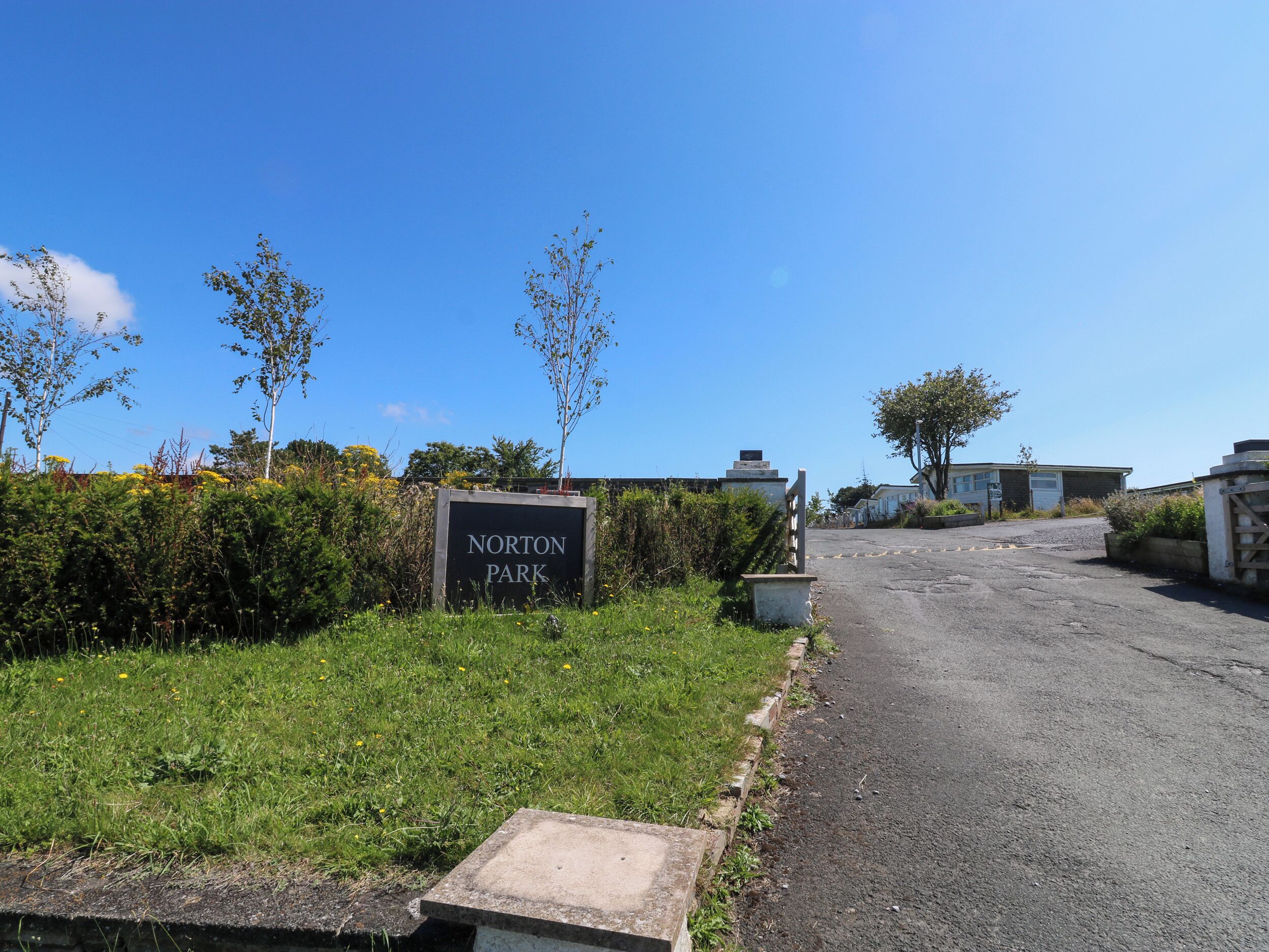 A sign for Norton Park with a paved road leading to a building.