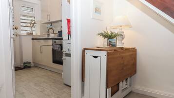 A kitchen with white cabinets, a refrigerator, and a wooden bench with a lamp.