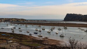 A harbor with numerous boats docked, a sandy beach, and buildings in the background. - Pie Cottage (Teignmouth)