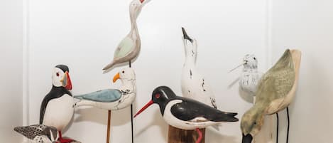 Eine Sammlung aus Vogelskulpturen auf Holzwürfeln vor einer weißen Wand.