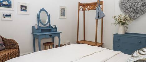 Una camera da letto con un letto, una cassettiera blu, un armadio in legno, una toeletta blu con uno specchio e decorazioni murali.