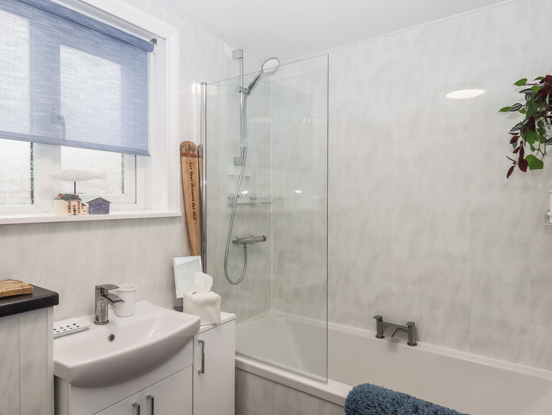 Ein modernes Badezimmer mit einer gläsernen Duschkabine, einem weißen Waschbecken und einer Badewanne.