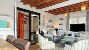 A cozy living room with a wooden ceiling, a television, and a bookshelf.