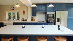 Een moderne keuken met een groot kookeiland, blauwe keukenkastjes en houten krukken.