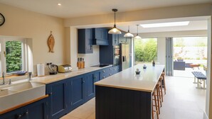 Een moderne keuken met donkerblauwe kastjes, een groot kookeiland en hanglampen.