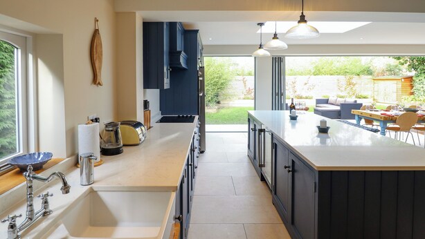 Een moderne keuken met een groot eiland, dubbele spoelbakken en uitzicht op de achtertuin.
