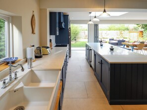Een moderne keuken met een groot eiland, dubbele spoelbakken en uitzicht op de achtertuin.