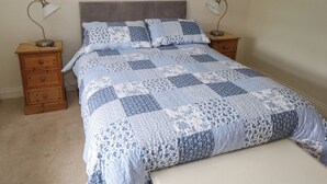 A bedroom with a bed, two nightstands, and two wall lamps. - Kivvy Cottage (Carrigallen)