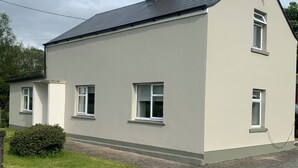 A two-story house with a flat roof, three windows, and a chimney. - Kivvy Cottage (Carrigallen)