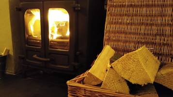 A room with a wood-burning stove and a wicker basket filled with firewood.