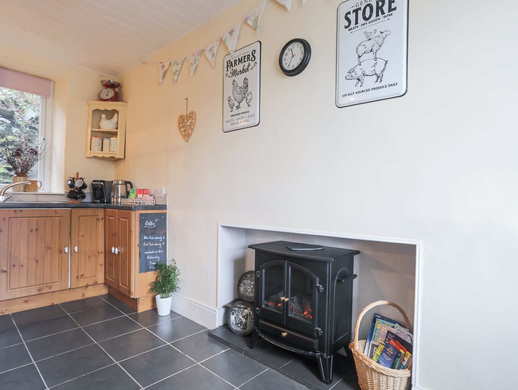 A cozy kitchen with wooden cabinets, a black stove, and a chalkboard menu.