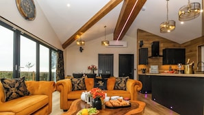 A modern living room with a wooden coffee table, sofas, and a dining area with a kitchen in the background. - Routhorpe Lodge (Driffield)
