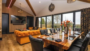 A modern dining area with a wooden table, black chairs, and a large window offering a view of the outdoors. - Routhorpe Lodge (Driffield)