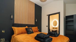 A modern bedroom with a large bed, a bedside table, a mirror, and a wardrobe. - Routhorpe Lodge (Driffield)