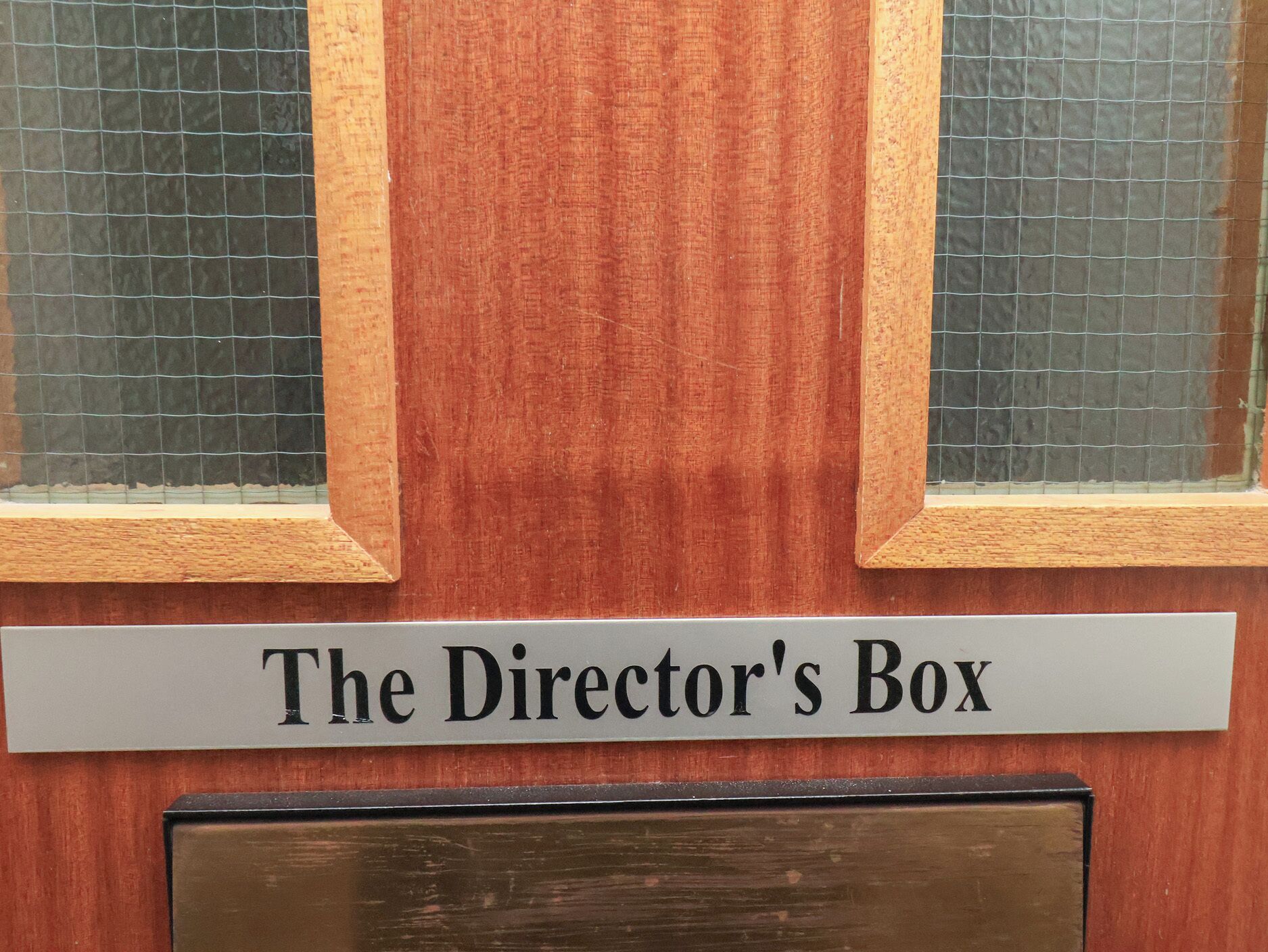 Une porte en bois sur laquelle est apposée une plaque indiquant : « Loge du directeur ».